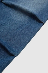 Close-up of heavy denim fabric texture and twill weave on loose wide-leg jeans