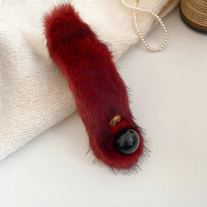 Detail of plush faux fur hair clip in dark red with black bead and gold accents