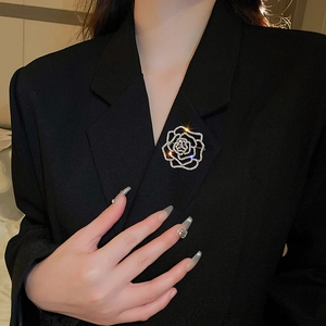 Detailed view of silver hollow camellia brooch with rhinestones on black blazer lapel