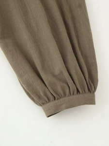 Detail of olive green linen shirt sleeve with elegant pleated cuffs and visible fabric texture