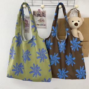 Detail of green and brown canvas tote bags with blue floral pattern in a cozy room