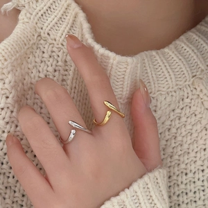Close-up of minimalist wave-shaped sterling silver rings in gold and silver finish