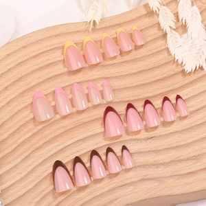 French tip press-on nail kit with pink, yellow, and burgundy almond shapes on wood