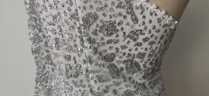 Détail de l'encolure en dentelle blanche avec motif léopard à paillettes argentées