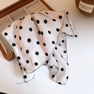 Gros plan d'un foulard vintage à pois noirs avec texture soyeuse sur bois