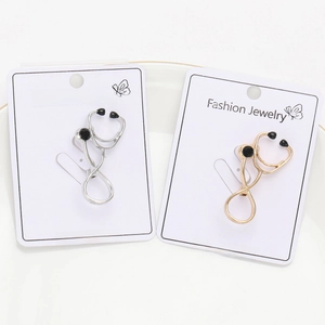 Detailed view of silver and gold stethoscope brooches on a Fashion Jewelry card