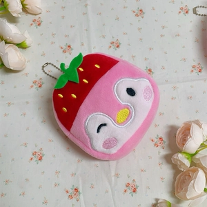 Close-up of strawberry penguin plush coin purse with metal chain on floral background