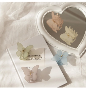 Detail shot of butterfly hair claws in matte resin with macaron colors on a mirror