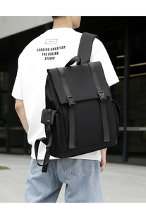 Detail view of a black nylon backpack with flap cover and buckle closures for men