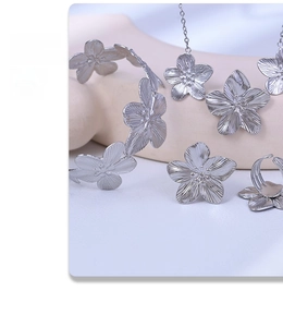 Silver flower jewelry set featuring a necklace, bracelet and ring on a soft background