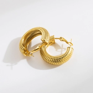 Macro detail of chunky gold snake-scale textured C-shaped hoop earrings for women