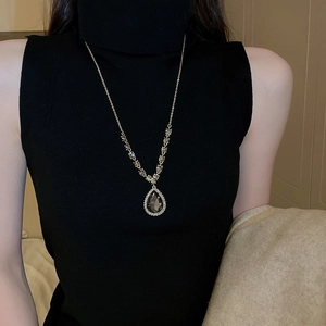 Detail of water drop pendant necklace with dark gemstone and rhinestones on a model