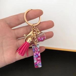 Detailed view of pink resin letter keychain with golden ring and sparkling star sequins