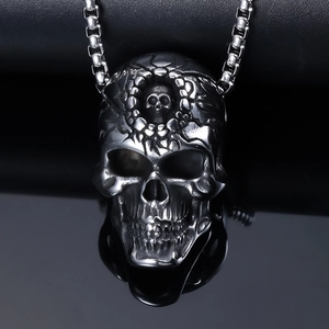 Macro view of gothic skull pendant with stainless steel chain on a reflective black surface