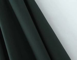 Close-up of deep green fabric showing high-quality texture and subtle luster on the dress