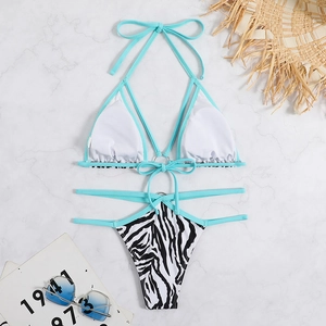 Sexy zebra print bikini set with green halter neck and decorative metal ring on marble
