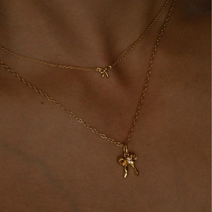 Elegant layered gold necklaces featuring small and large bow pendants with pearl details