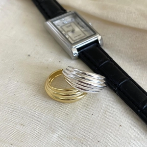 Close-up of gold and silver wave-shaped rings with metal texture on linen background