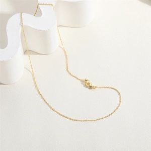 Detail der minimalistischen vergoldeten Gliederkette mit Karabinerverschluss und Perle