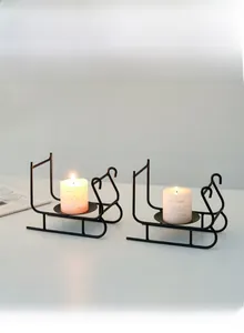 Detail of Nordic black metal sleigh candle holders with white pillar candles on a table