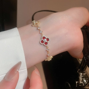 Close-up of 18k gold plated bracelet with red clover charm and sparkling zircon stones