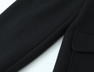 Close-up of the black wool blend coat showing high-density fabric texture and pocket detail