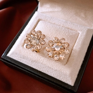 Detail view of 14K gold plated flower earrings with crystals in a black jewelry box