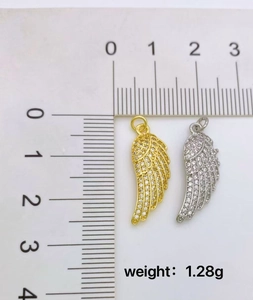 Macro shot of gold and silver wing pendants with cubic zirconia and 1.28g weight detail