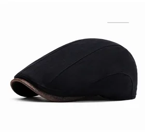 Detail shot of black newsboy cap with brown textured brim showing stitching and material