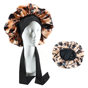 Detailed view of leopard print satin hair bonnet with wide elastic straps and silk texture