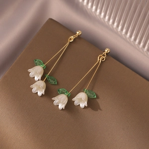 Detailed close-up of lily of the valley earrings with white petals and gold metal hooks
