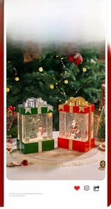 Close-up of lighted Christmas gift-box lanterns with glowing snow scene and Santa figure