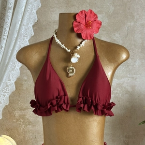 Detail of burgundy bikini top with ruffle trim on mannequin with hibiscus flower