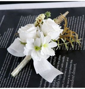 Detail view of white rose boutonniere with champagne ribbon on dark book background