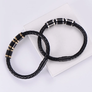 Men's braided leather bracelet with gold and silver magnetic clasp on marble base