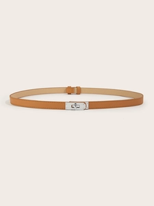 Detail of tan slim leather belt showing a silver metal turn-lock buckle on plain background