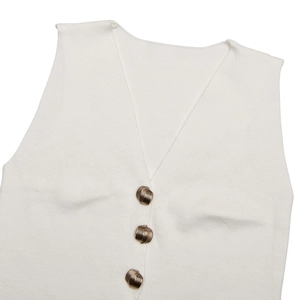 Dettaglio del gilet in maglia bianca con scollo a V e tre bottoni in metallo testurizzati