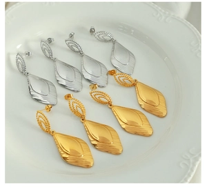 Detailed view of leaf-shaped earrings in gold and silver finish on a white plate
