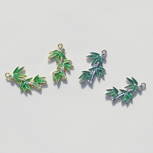 Detailed view of bamboo leaf charms in gold and silver finish with green enamel and rhinestones