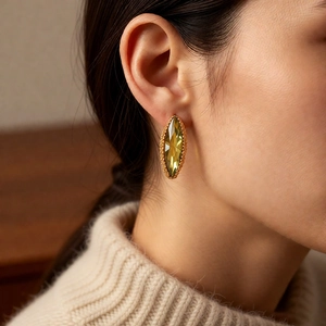 Detail of model wearing emerald green marquise cut stud earrings in gold base