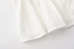 Macro detail of breathable white cotton linen fabric with pleated texture and fine stitching
