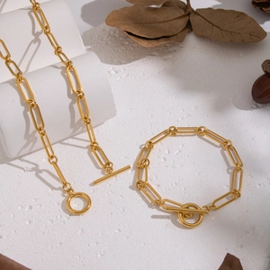 Minimalist gold paperclip chain necklace and bracelet set with toggle clasp on white surface