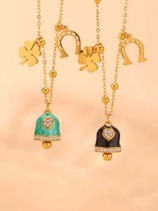 Detail view of 18K gold plated necklaces featuring enamel bell and clover charms