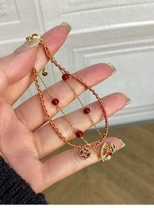 Detail of 18k gold plated double-layer bracelet with red beads and dragon coin charms