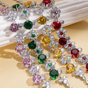 Luxury zircon flower necklace set with multi-color gemstones on white marble pedestal