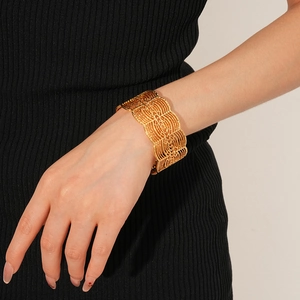 Nahaufnahme des breiten Vintage-Armreifs in Gold mit geometrischem Muster am Handgelenk