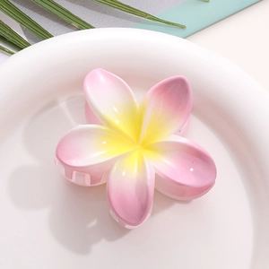 Close-up of pink gradient plumeria hair claw clip on a white decorative tray