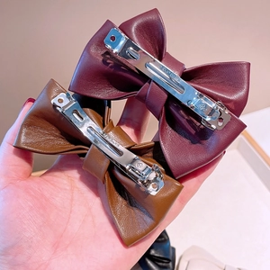 Détails du clip métallique et de la texture cuir des barrettes nœud vintage