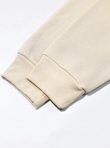 Dettaglio dei polsini a coste beige e del tessuto in pile di una tuta da uomo