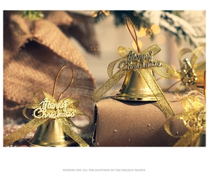 Close-up of golden Christmas bells with Merry Christmas lettering and golden ribbons